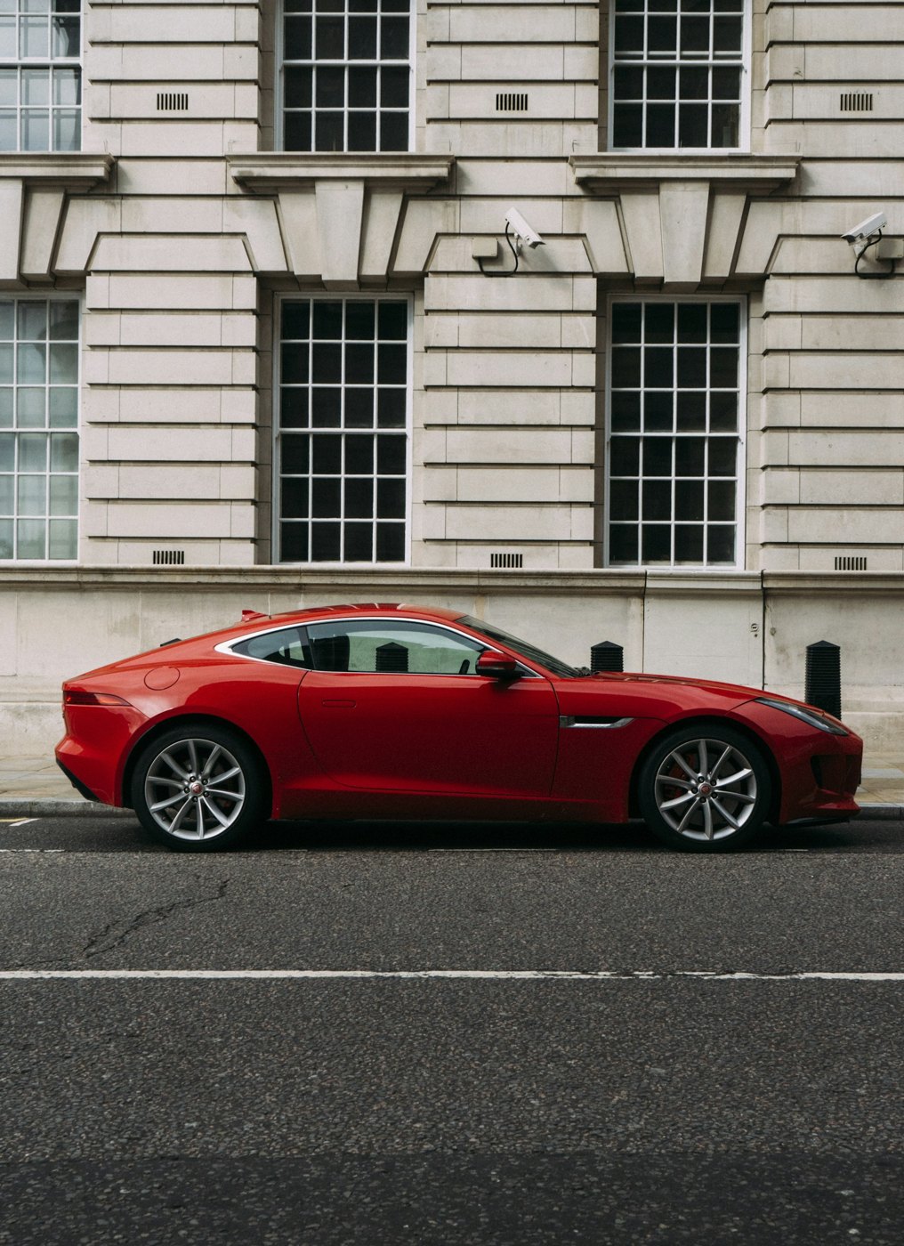 Red sports coupe parked beside a city building